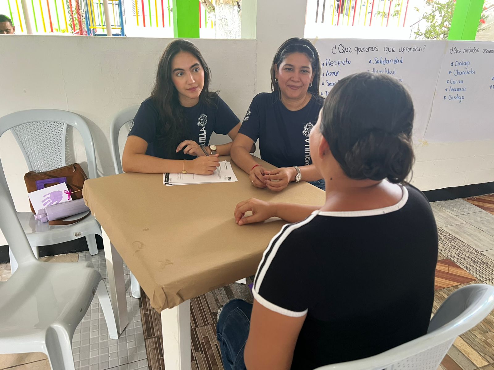 Funcionarias de la Alcaldía de Barranquilla escuchan con atención a una ciudadana durante una jornada de atención comunitaria.