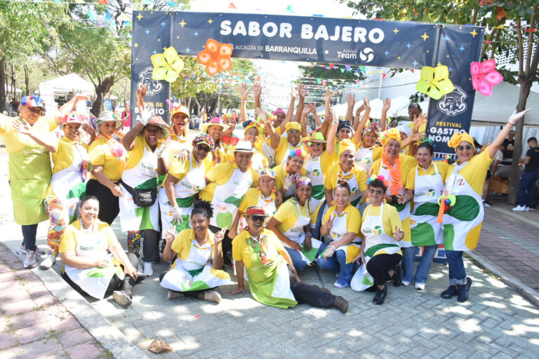 Grupo de cocineras sonrientes posan bajo el cartel “Sabor Bajero” en evento gastronómico en Barranquilla.
