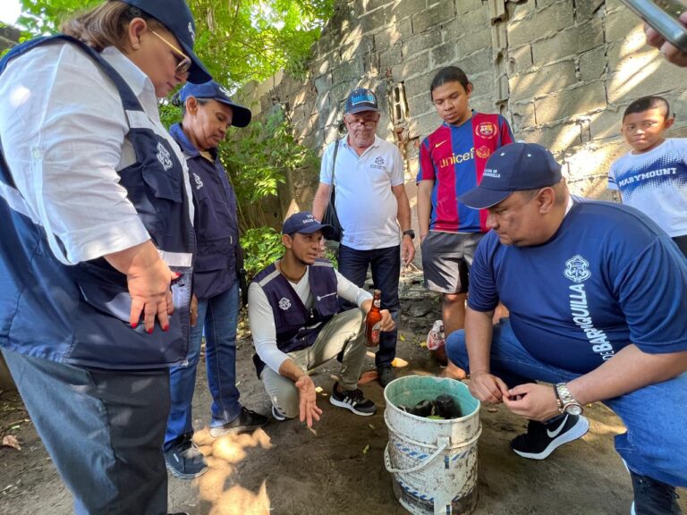 Funcionarios y comunidad inspeccionan balde con agua en búsqueda de criaderos del mosquito transmisor del dengue.
