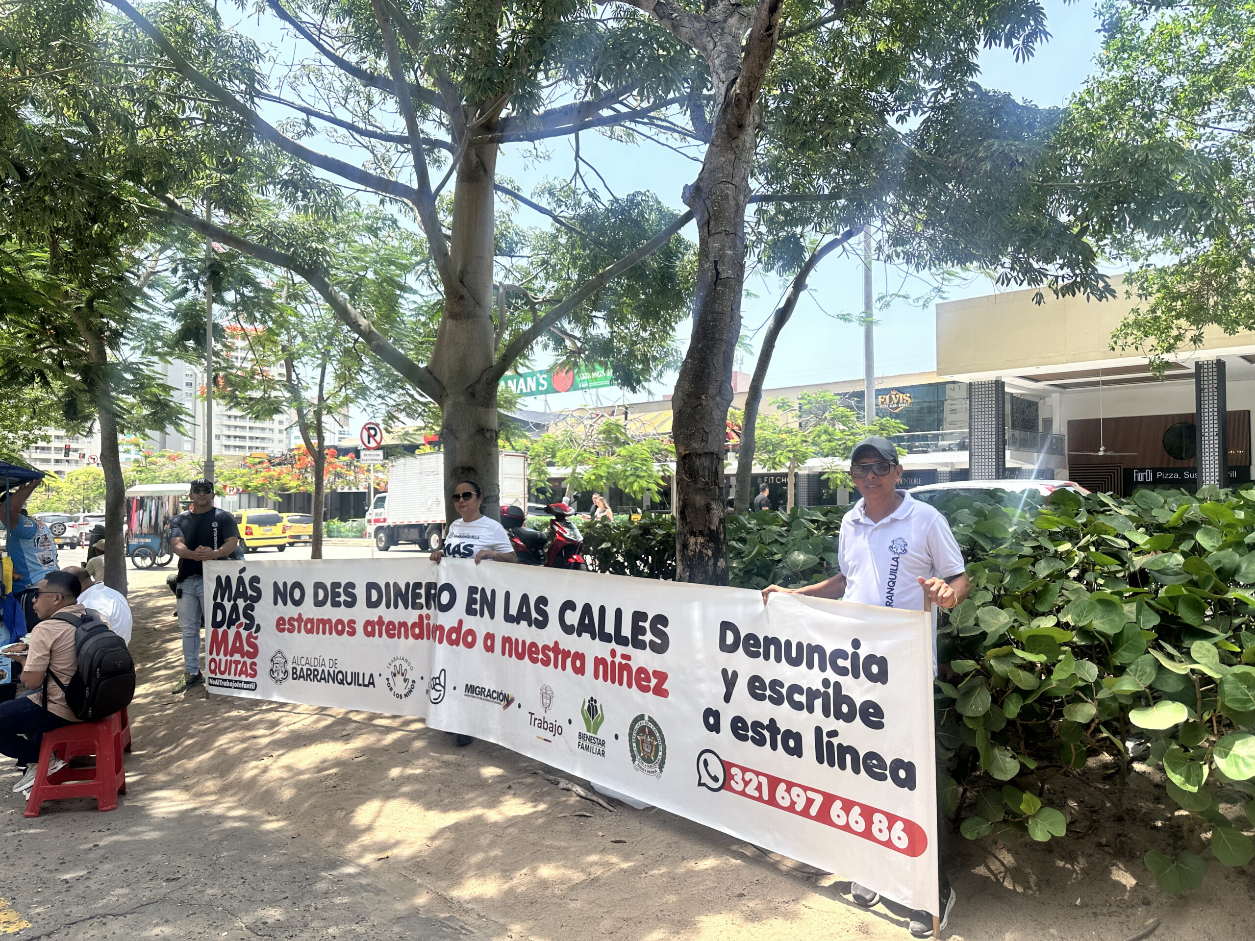 Funcionarios sostienen una pancarta con el mensaje: “No des dinero en las calles, estamos atendiendo a nuestra niñez”, como parte de la campaña “Más das, más quitas”.