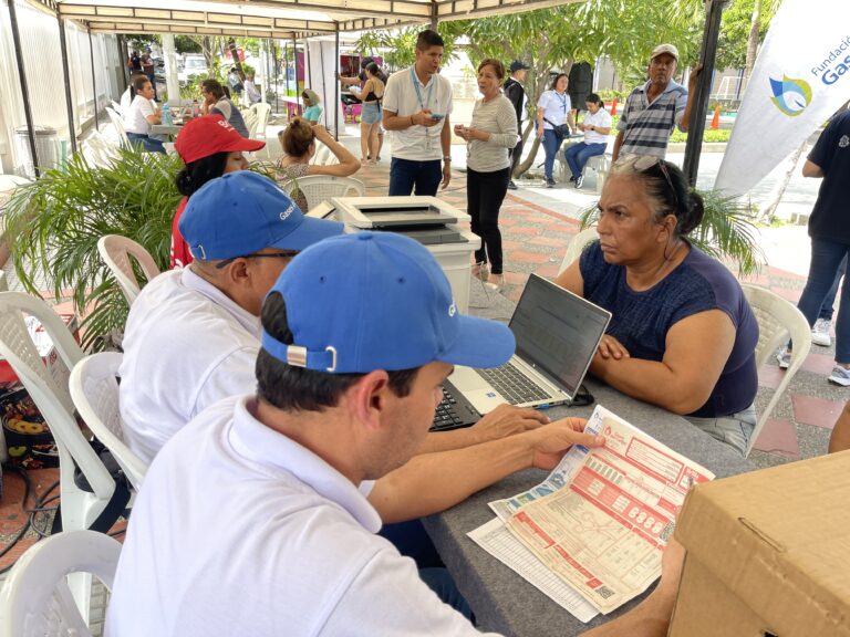 Funcionarios atienden a ciudadana durante jornada de brigada de servicios públicos.