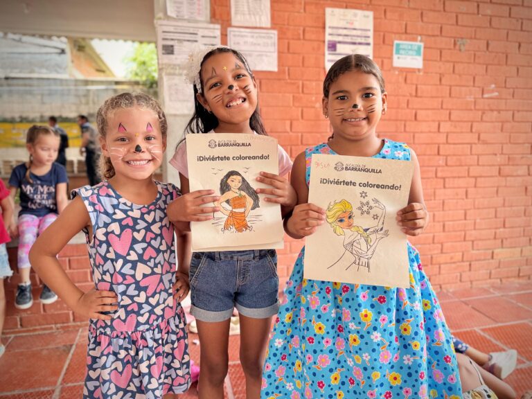 Tres niños muestran con orgullo sus dibujos coloreados durante una actividad recreativa organizada por la Alcaldía de Barranquilla. Además de recibir alimentación balanceada, los menores participan en juegos y dinámicas que promueven la convivencia, los valores y la creatividad.
