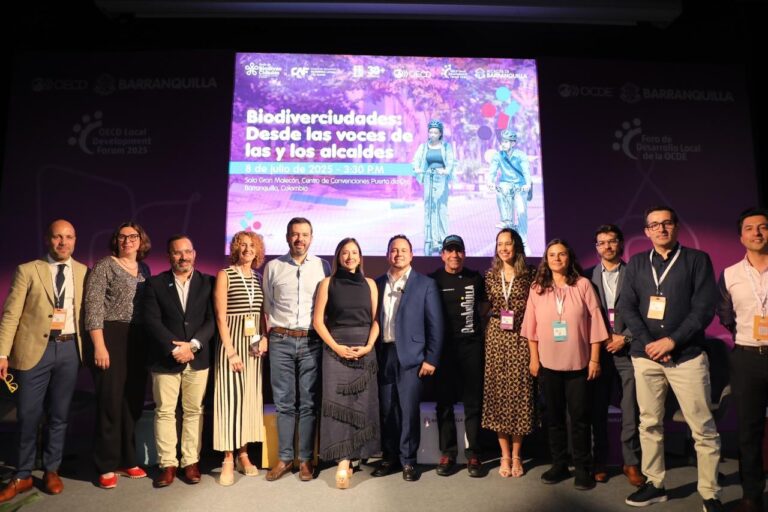 Grupo de expertos y autoridades posa frente a pantalla que anuncia “Biodiverciudades: desde las voces de los y las alcaldes”, en en evento OCDE 2025.