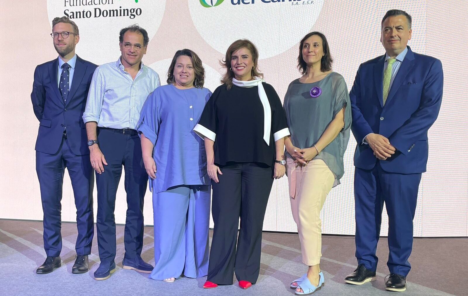 Grupo de expertos y autoridades posa frente a pantalla en evento OCDE 2025.