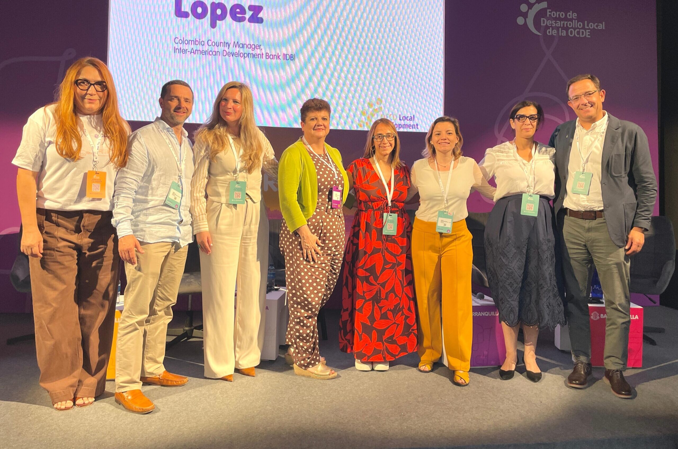 Grupo de expertos y autoridades posa frente a pantalla en evento OCDE 2025.