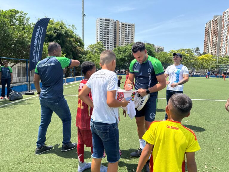 El exfutbolista Sebastián Viera firma una camiseta a un grupo de niños en una cancha sintética durante una jornada del programa “Jugando por un futuro a otro nivel”.