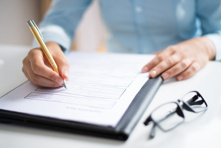 Primer plano de una persona firmando un documento.