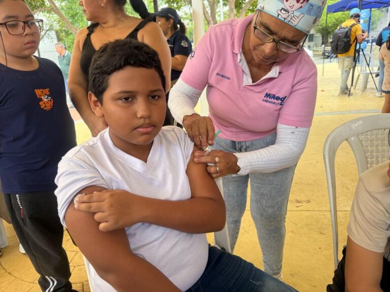 Profesional de la salud aplica una vacuna en el brazo de un niño sentado.