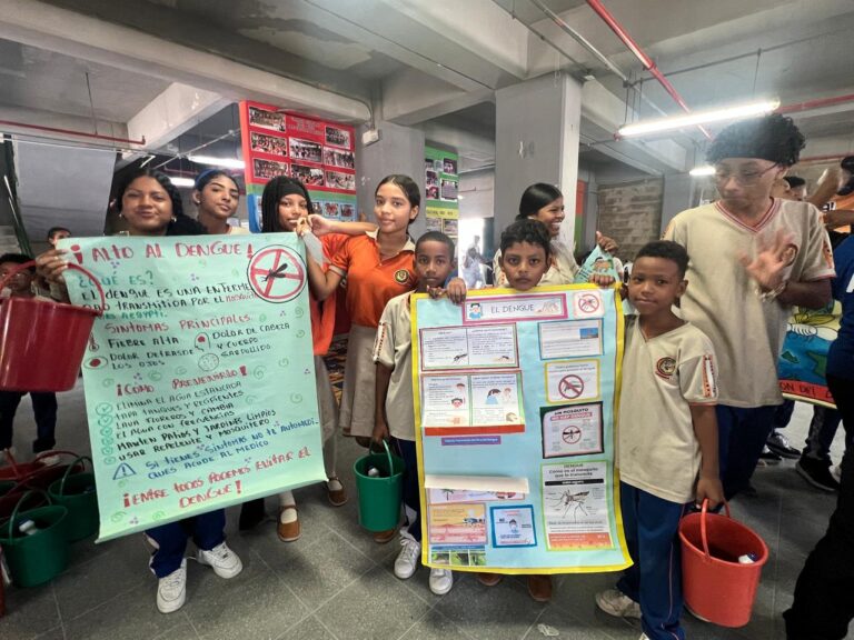 Estudiantes participan en jornada pedagógica con carteles y baldes para promover la prevención del dengue.