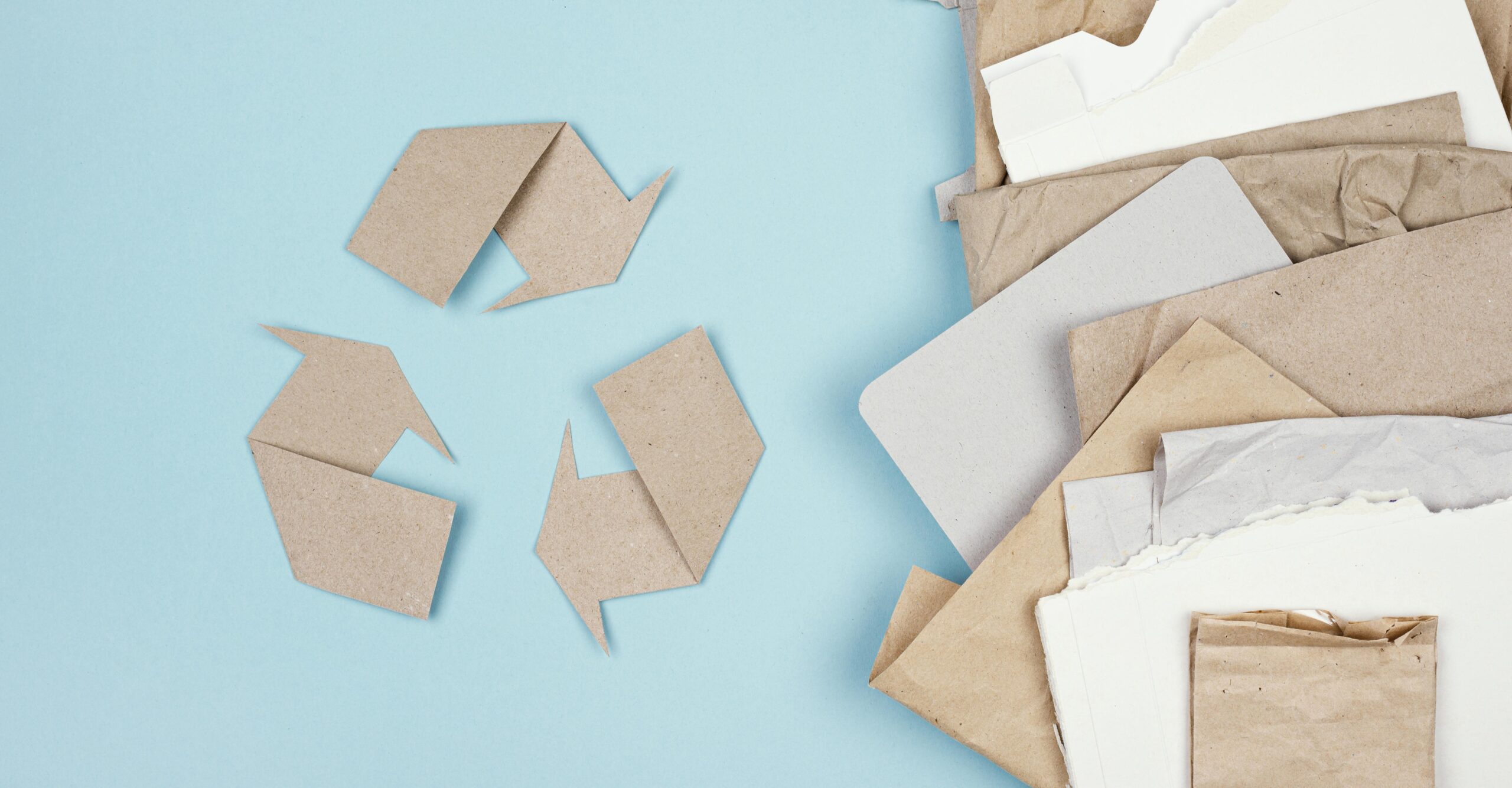 Simbolo del reciclaje con papel ecologico en fondo azul.