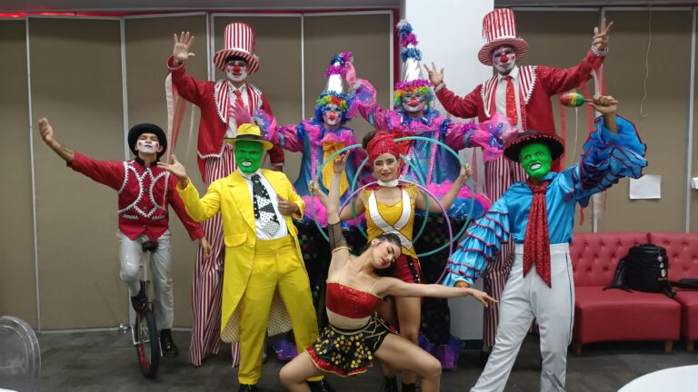 Grupo de artistas con disfraces coloridos posando sonrientes.