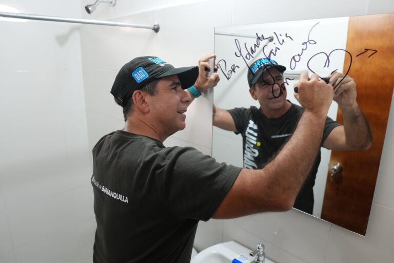 El alcalde Char firma un espejo en el baño recién renovado, como parte del programa de Mejoramiento de Vivienda.