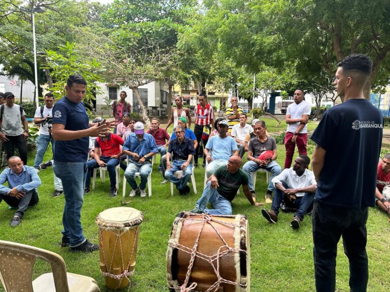 Funcionario de la Alcaldía de Barranquilla interviene de pie frente a un grupo de hombres reunidos al aire libre.