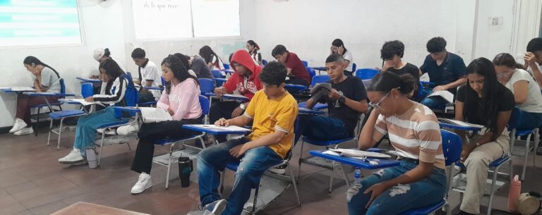Grupo de estudiantes presentan pruebas escritas en el aula de clases.