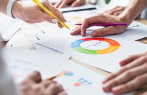 Personas analizan y discuten información gráfica representada en diagramas circulares y documentos impresos sobre una mesa.