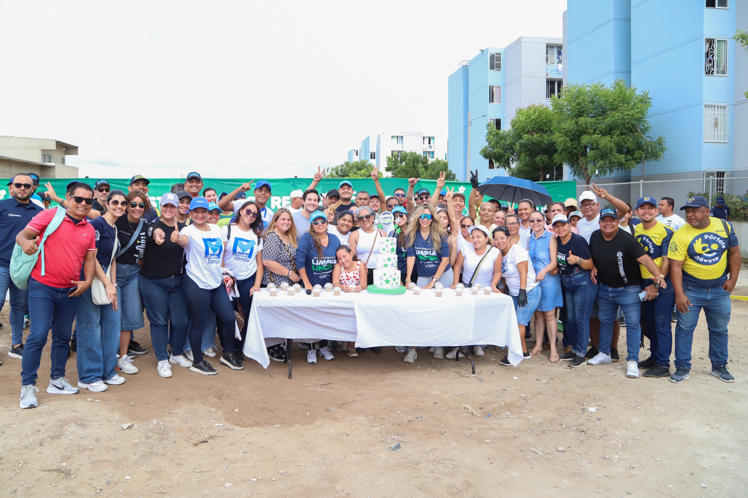 Un grupo de personas sonrientes posa para la cámara frente a una mesa con pastel y vasos.