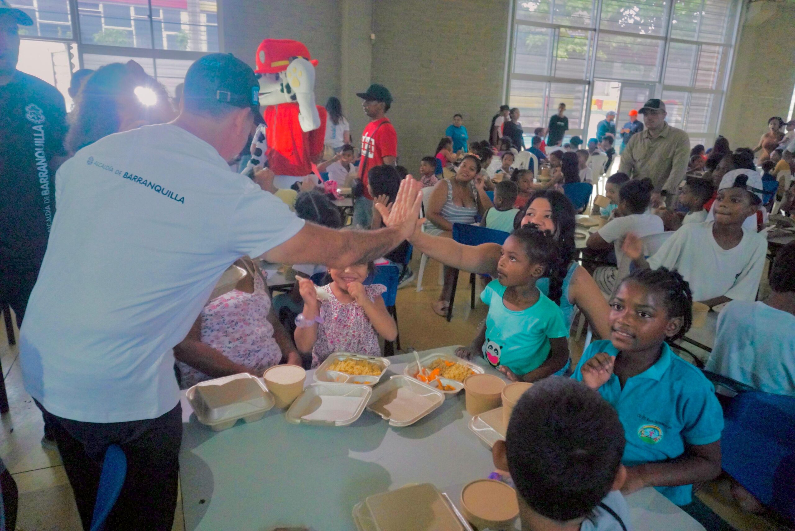 Alcalde Char entrega desayunos en comedor comunitario y comparte un choque de manos con una asistente.