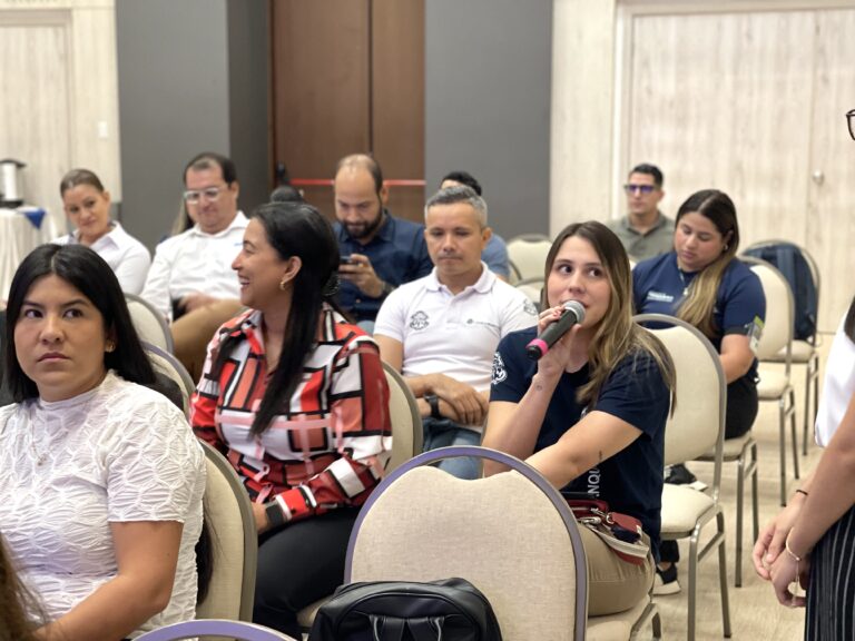Asistente participa con micrófono en mano durante el Primer Encuentro con Enlaces de Cooperación Internacional, mientras el público escucha con atención.