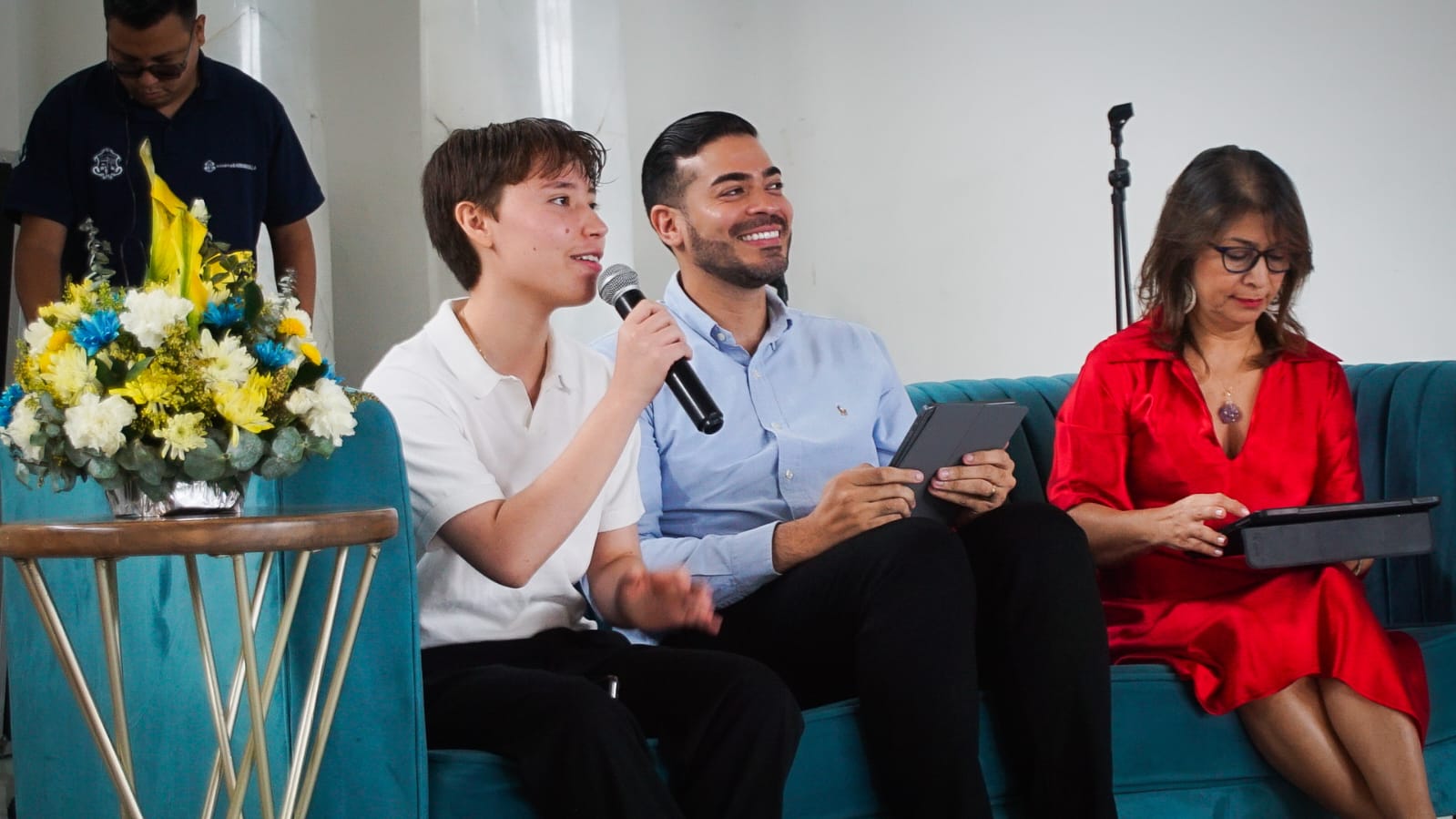 Joven hablando con micrófono durante cierre de Escuela Emprendedora junto a otros panelistas