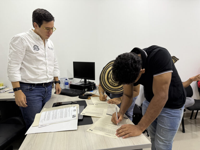 Representantes de la comunidad indigena firman su acta de posesión en presencia del alcalde local de NCH
