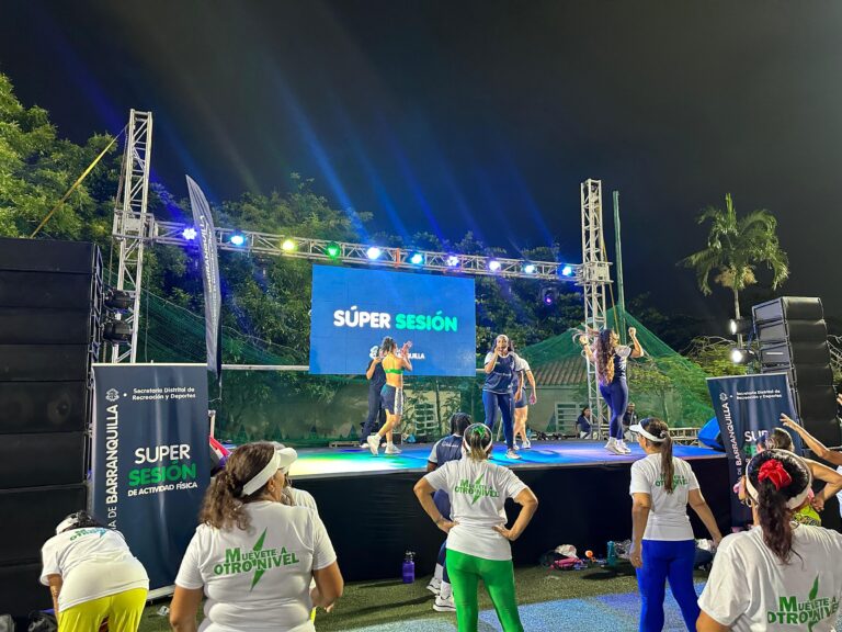 Entrenadores lideran súper sesión de actividad física en tarima junto a participantes en Barranquilla.