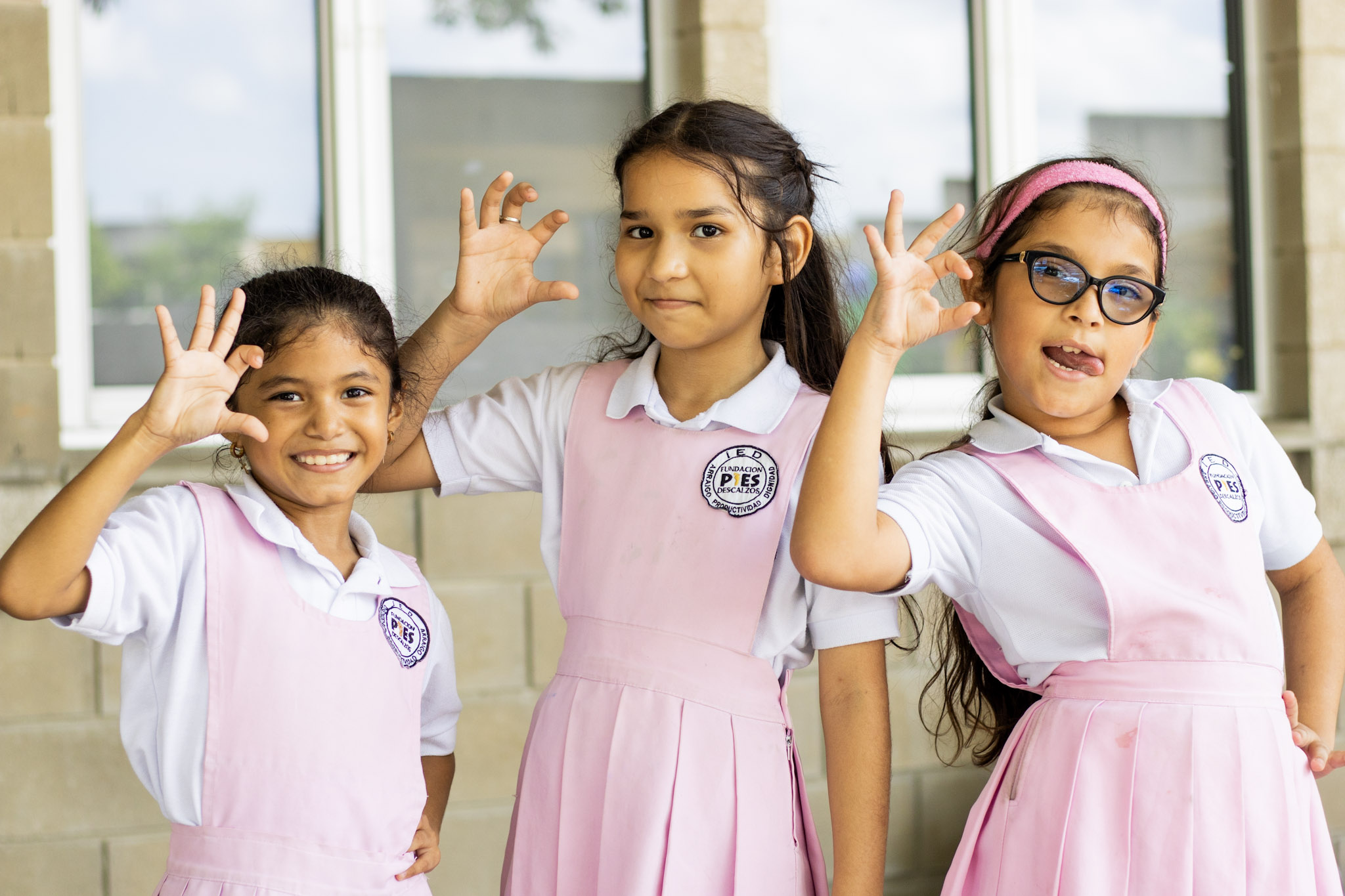 Niñas del colegio Pies descalzos posando con la mano de portarse chévere