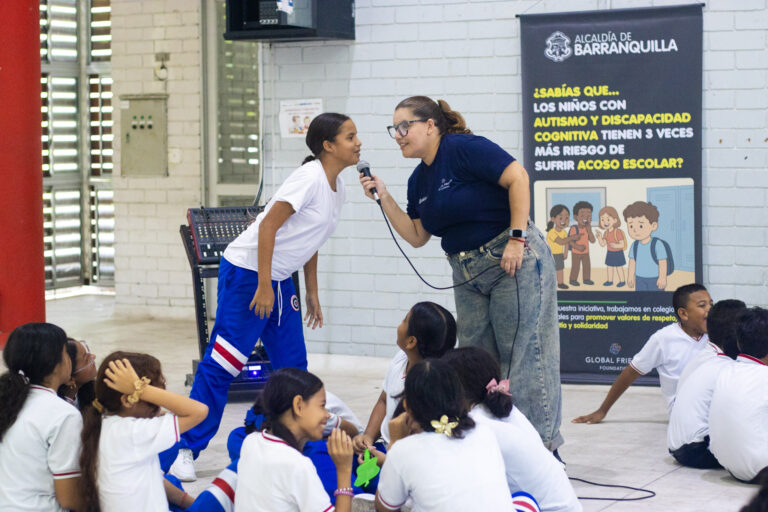 Psicóloga compartiéndole el micrófono a un estudiante para que participe. 