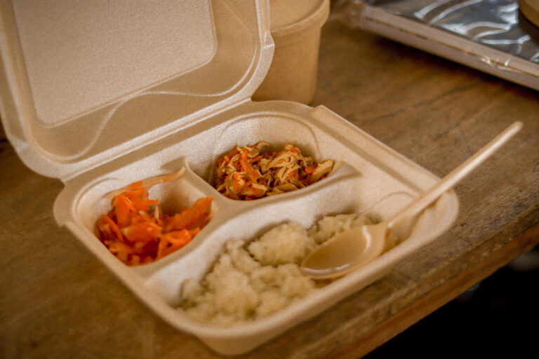 Caja de comida contiene arroz, pollo y ensalada de zanahoria. 