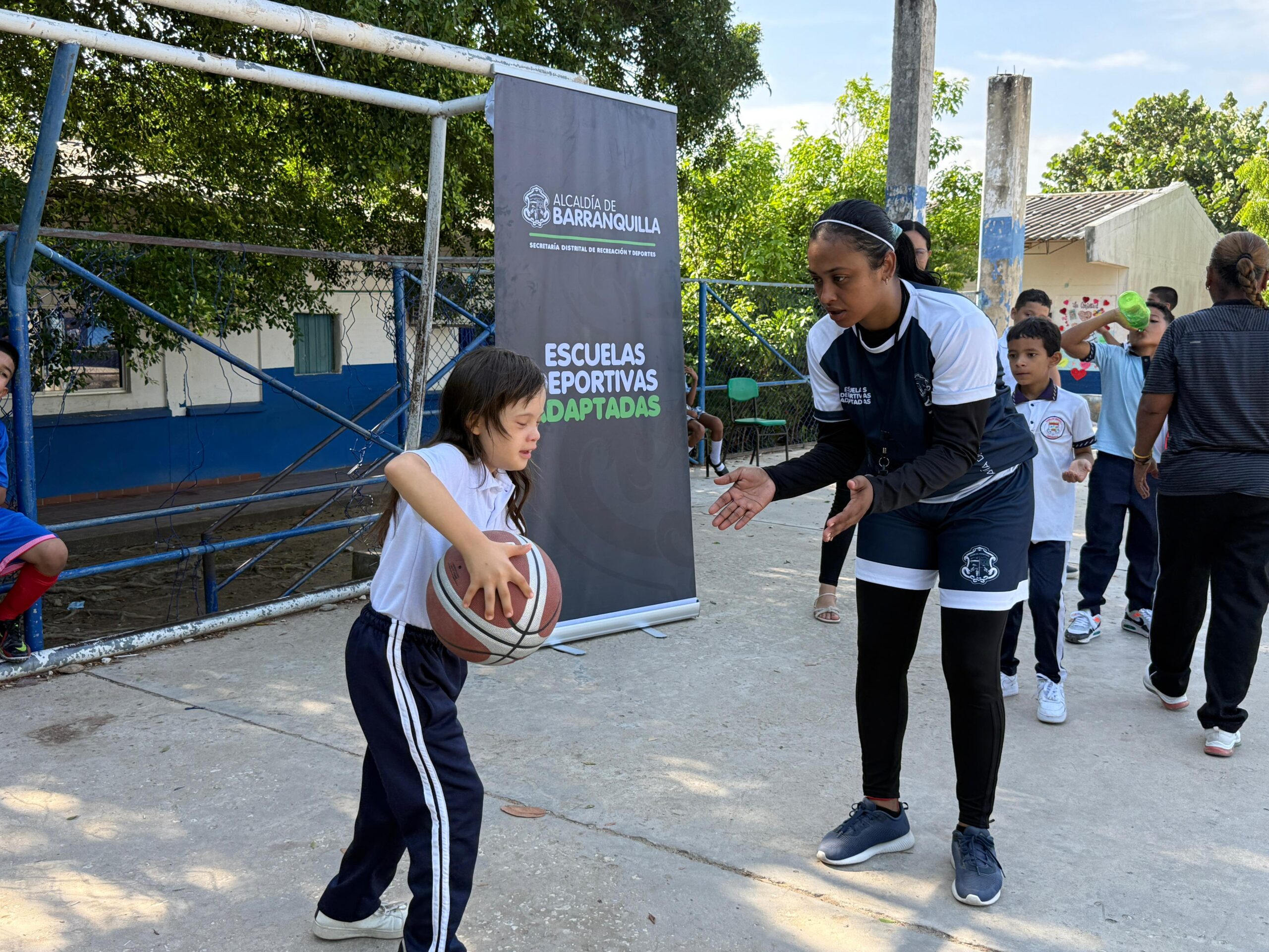 Usuaria de nuestras Escuelas deportivas adptadas jugando con una instructora al baloncesto