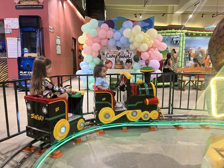 Niñas disfrutando de un paseo en tren en un juego de atracción infantil.