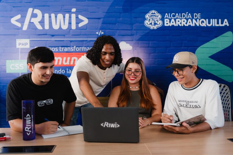 Cuatro jóvenes trabajan colaborativamente frente a un portátil en un entorno tecnológico del programa RIWI, impulsado por la Alcaldía de Barranquilla.