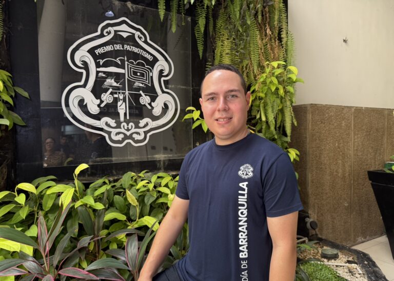 Funcionario con camiseta institucional, con fondo con el logo.