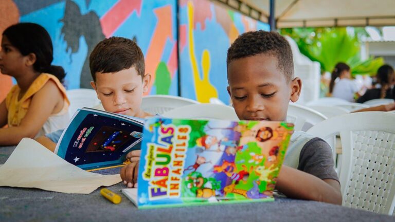 Niños sentados cada uno con un libro abierto; en primer plano se destaca un libro titulado “Fábulas Infantiles” con ilustraciones coloridas.