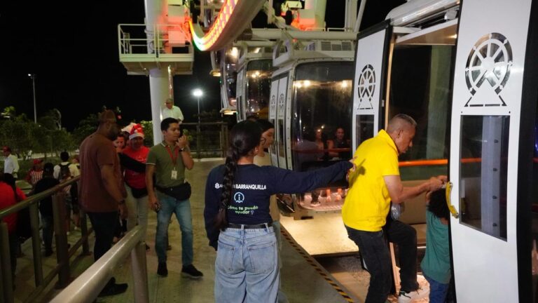Personas abordando cabinas de una noria en una plataforma iluminada durante la noche, con señalización en las puertas y ambiente al aire libre.
