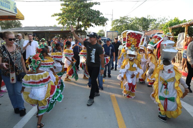 El Acalde Alejandro Char, saludando mientras unos niños tiene traje de Congo mientras van bailando.