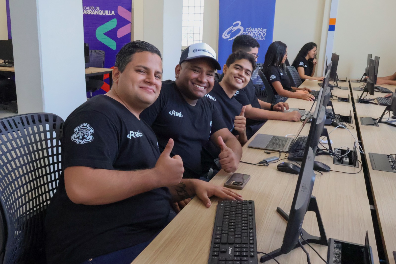 Jóvenes estudiantes sonriendo enfrente de computadores durante una clase