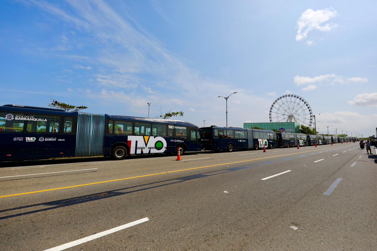Fila de buses de transmetro alineados uno tras otro en el carril derecho ubicados en el Gran malecón y atrás se observa la Luna del Rio