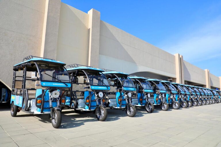 Fila ordenada de bicicletas eléctrica, estacionados uno junto a otro en un espacio amplio y pavimentado.