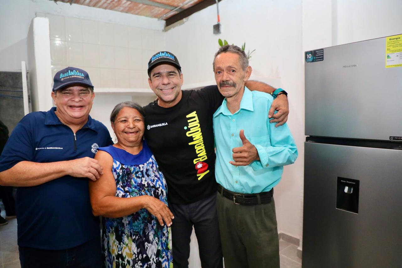 El Acalde Alejandro Char dentro de una vivienda recién mejorada esta abrazada con dos adultos mayores.