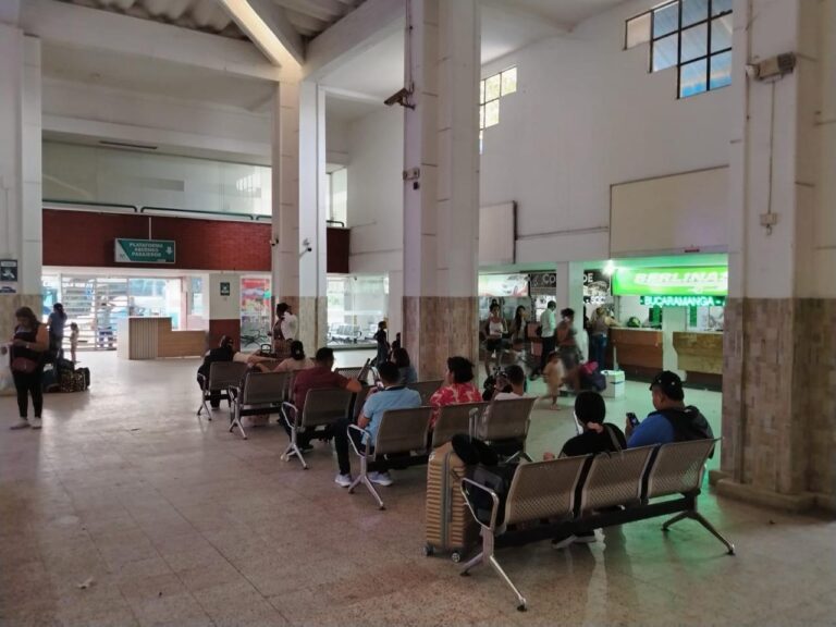 Terminal de transporte de barranquilla, hay varias bancas metálicas con asientos grises, donde varias personas están sentadas esperando.