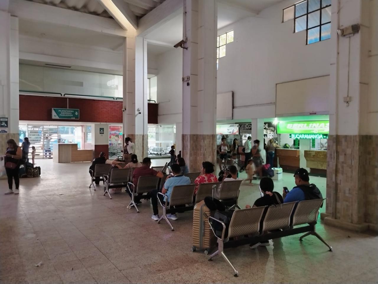 Terminal de transporte de barranquilla, hay varias bancas metálicas con asientos grises, donde varias personas están sentadas esperando.