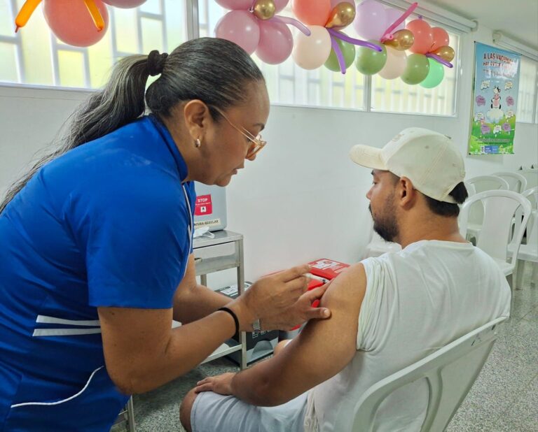 Enfermera aplicando dosis de vacuna en brazo a hombre.