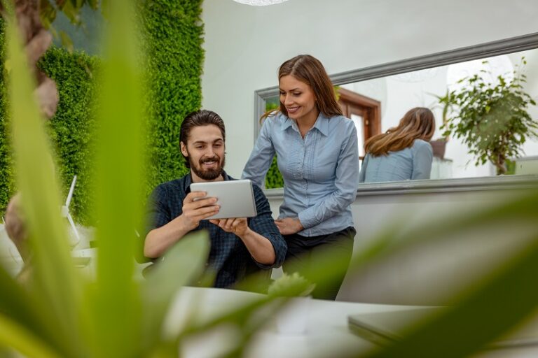 Joven sosteniendo una tablet mientras está sentado en una oficina con jardines y plantas