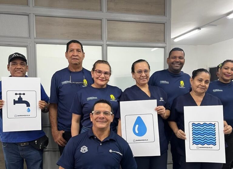 Funcionarios y miembros de servicios generales muestran afiches de una gota de agua, grifo, agua en movimiento