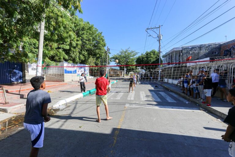 Nilos jugando raquetas en una cuadra con personas observando